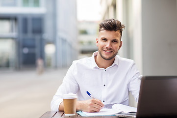 Image showing man with laptop and coffee at city cafe