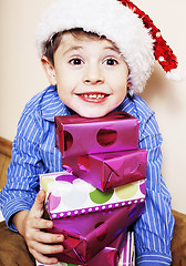 Image showing little cute boy with Christmas gifts at home. close up emotional