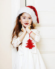 Image showing little cute girl in santas red hat waiting for Christmas gifts. 