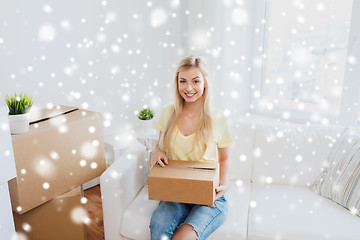 Image showing smiling young woman with cardboard box at home