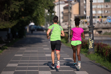 Image showing young smiling multiethnic couple jogging in the city