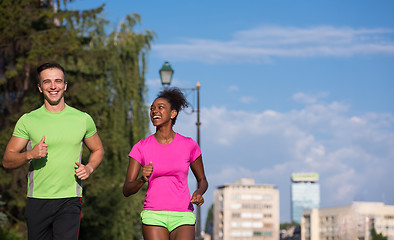 Image showing young smiling multiethnic couple jogging in the city