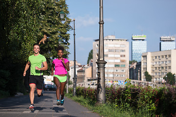 Image showing young smiling multiethnic couple jogging in the city