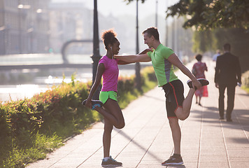 Image showing jogging couple warming up and stretching in the city