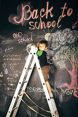 Image showing little cute real boy at blackboard in classroom, back to school,