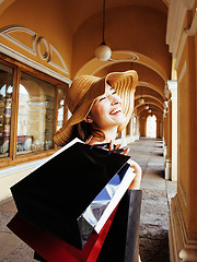 Image showing young pretty smiling woman in hat with bags on shopping at store