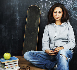 Image showing young cute teenage girl in classroom at blackboard seating on ta