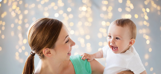 Image showing happy young mother with little baby over lights