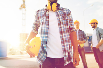 Image showing close up of builder holding hardhat at building