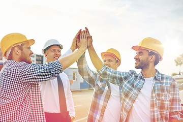 Image showing close up of builders in hardhats making high five