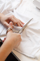 Image showing Girl cuts cloth with scissors