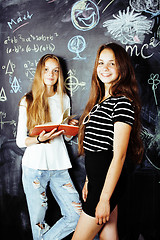 Image showing back to school after summer vacations, two teen real girls in classroom with blackboard painted together