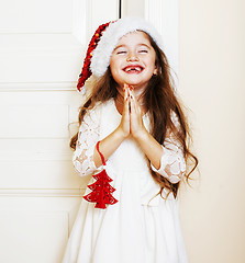 Image showing little cute girl in santas red hat waiting for Christmas gifts. 