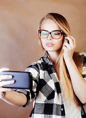 Image showing young pretty blond hipster girl making selfie on warm brown back