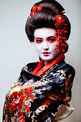 Image showing young pretty geisha in black kimono among sakura, asian ethno