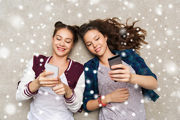 Image showing happy teenage girls lying on floor with smartphone