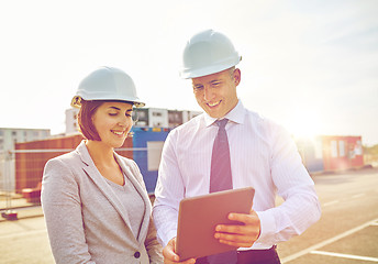 Image showing happy builders in hardhats with tablet pc outdoors