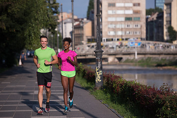 Image showing young smiling multiethnic couple jogging in the city