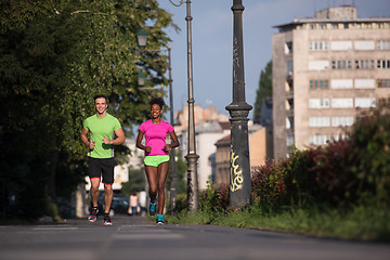 Image showing young smiling multiethnic couple jogging in the city