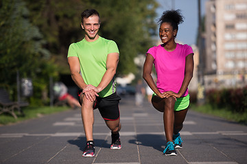 Image showing jogging couple warming up and stretching in the city