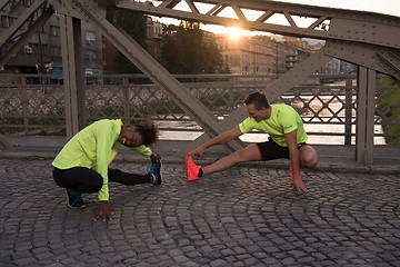 Image showing jogging couple warming up and stretching in the city