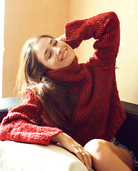 Image showing young pretty real woman in red sweater and scarf all over her face smiling at home, winter positive, lifestyle people concept