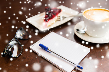 Image showing close up of notebook with pen, coffee cup and cake