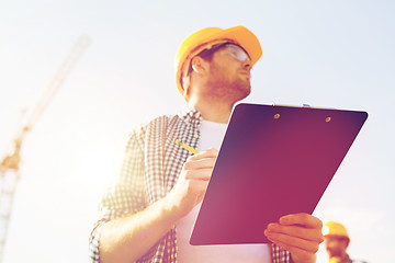 Image showing builder in hardhat with clipboard outdoors
