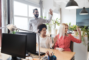 Image showing happy creative team waving hands in office