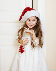 Image showing little cute girl in santas red hat waiting for Christmas gifts. holiday lifestyle people concept