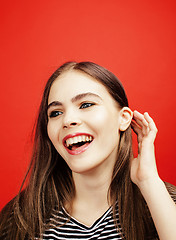 Image showing young pretty emitonal posing teenage girl on bright red background, happy smiling lifestyle people concept