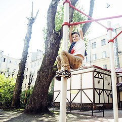 Image showing little cute blond boy hanging on playground outside, alone training with fun, lifestyle children concept