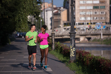 Image showing young smiling multiethnic couple jogging in the city