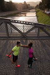 Image showing jogging couple warming up and stretching in the city