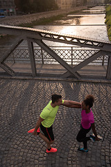 Image showing jogging couple warming up and stretching in the city