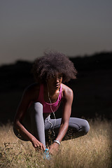 Image showing black woman runner tightening shoe lace