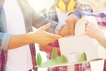 Image showing close up of builders with paper house model