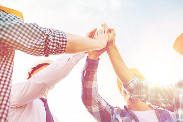 Image showing close up of builders in hardhats making high five