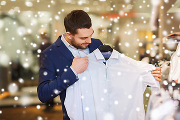 Image showing happy young man choosing clothes in clothing store