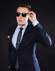 Image showing young pretty business man standing on black background, modern hairstyle, talking on phone emotional