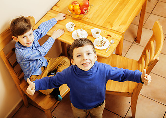 Image showing little cute boys eating dessert on wooden kitchen. home interior. smiling adorable friendship together forever friends, lifestyle people concept