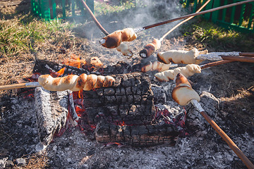 Image showing Bread on sticks over an outdoor campfire