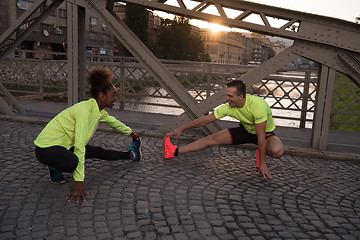 Image showing jogging couple warming up and stretching in the city