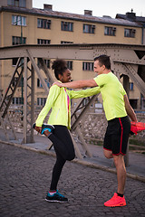 Image showing jogging couple warming up and stretching in the city