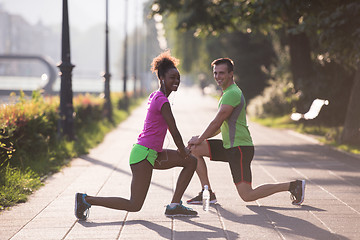 Image showing jogging couple warming up and stretching in the city