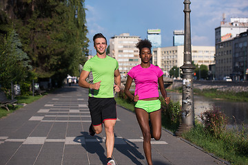 Image showing young smiling multiethnic couple jogging in the city