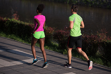 Image showing young smiling multiethnic couple jogging in the city