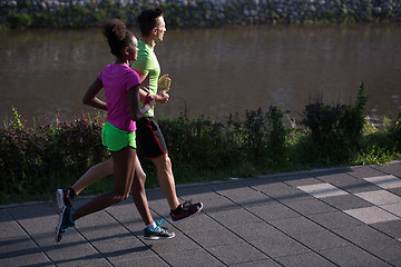 Image showing young smiling multiethnic couple jogging in the city