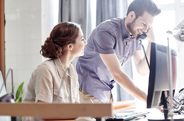 Image showing happy creative team calling on phone in office