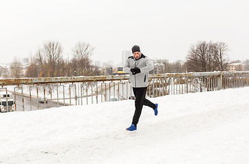 Image showing man with earphones running along winter bridge